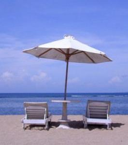 Beach chairs under an umbrella on the sand at the beach.